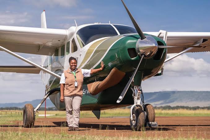A crew member standing beside the propeller of a Cessna Caravan 208 on a bush airstrip