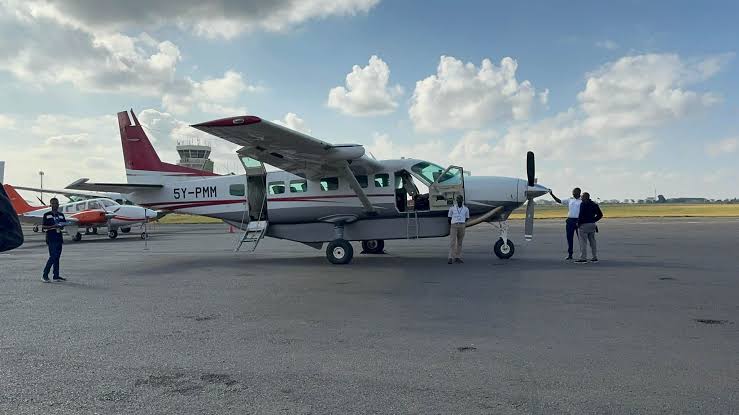 A Cessna Caravan 208 parked on an airport apron with crew standing nearby